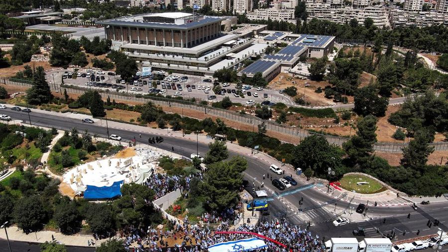 Pandangan dari udara menunjukkan pengunjuk rasa memegang bendera Israel selama demonstrasi menentang Perdana Menteri Israel Benjamin Netanyahu dan perombakan yudisial pemerintah koalisi nasionalisnya di dekat Knesset, parlemen Israel di Jersusalem 24 Juli 2023. (REUTERS/Ilan Rosenberg)