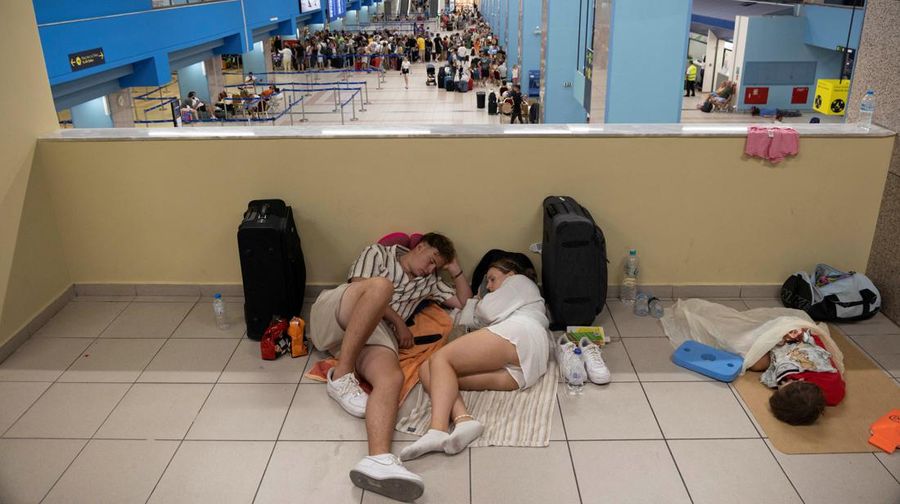 Wisatawan tidur sambil menunggu pesawat berangkat di bandara, setelah dievakuasi menyusul kebakaran hutan di pulau Rhodes, Yunani, (24/7/2023). (REUTERS/NICOLAS ECONOMOU)