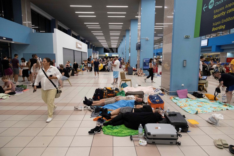 Wisatawan tidur sambil menunggu pesawat berangkat di bandara, setelah dievakuasi menyusul kebakaran hutan di pulau Rhodes, Yunani, (24/7/2023). (REUTERS/NICOLAS ECONOMOU) Wisatawan tidur sambil menunggu pesawat berangkat di bandara, setelah dievakuasi menyusul kebakaran hutan di pulau Rhodes, Yunani, (24/7/2023). (REUTERS/NICOLAS ECONOMOU)