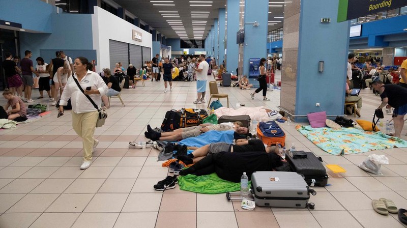 Wisatawan tidur sambil menunggu pesawat berangkat di bandara, setelah dievakuasi menyusul kebakaran hutan di pulau Rhodes, Yunani, (24/7/2023). (REUTERS/NICOLAS ECONOMOU)