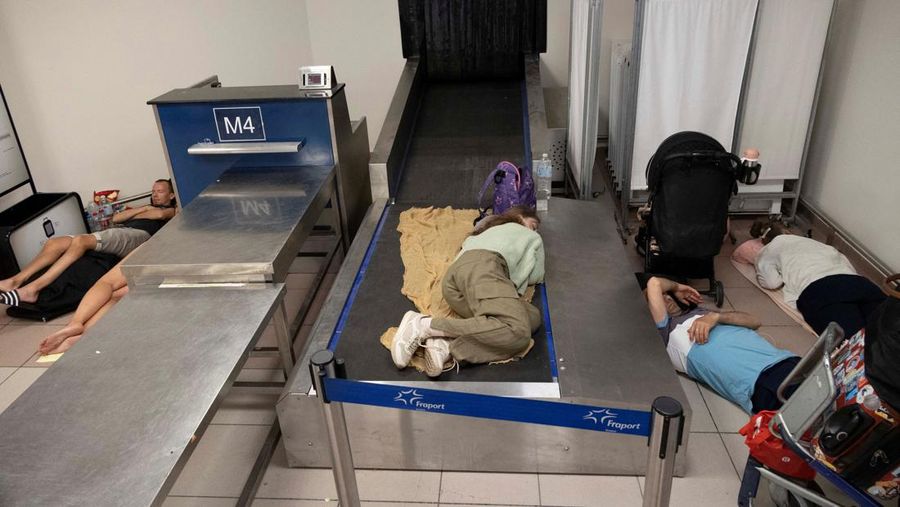 Wisatawan tidur sambil menunggu pesawat berangkat di bandara, setelah dievakuasi menyusul kebakaran hutan di pulau Rhodes, Yunani, (24/7/2023). (REUTERS/NICOLAS ECONOMOU)