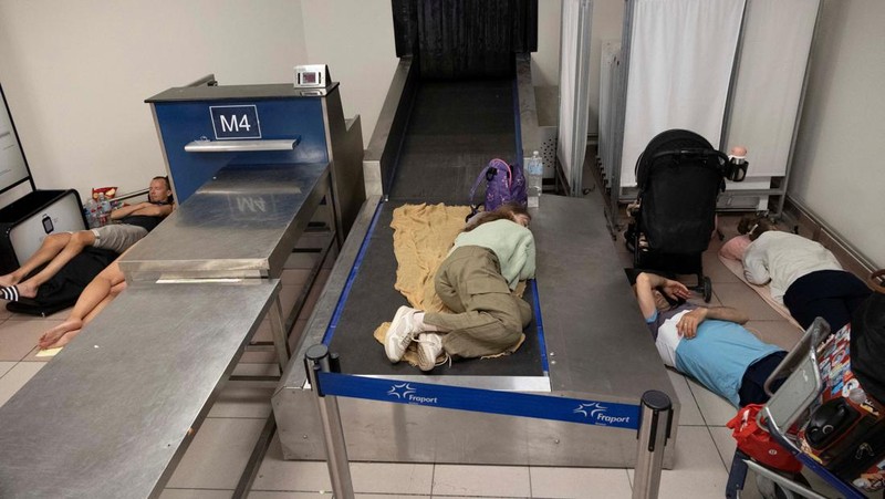 Wisatawan tidur sambil menunggu pesawat berangkat di bandara, setelah dievakuasi menyusul kebakaran hutan di pulau Rhodes, Yunani, (24/7/2023). (REUTERS/NICOLAS ECONOMOU)