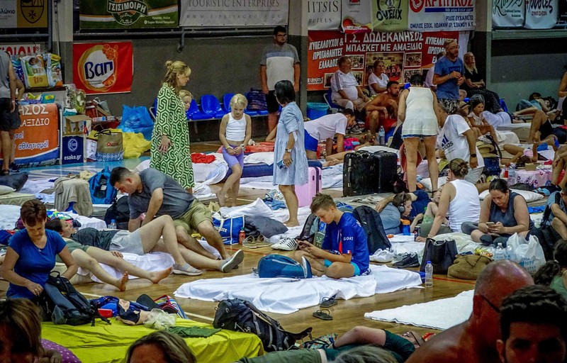 Wisatawan tidur sambil menunggu pesawat berangkat di bandara, setelah dievakuasi menyusul kebakaran hutan di pulau Rhodes, Yunani, (24/7/2023). (REUTERS/NICOLAS ECONOMOU)