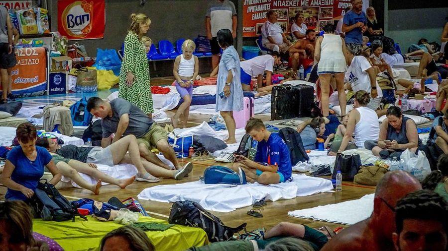 Wisatawan tidur sambil menunggu pesawat berangkat di bandara, setelah dievakuasi menyusul kebakaran hutan di pulau Rhodes, Yunani, (24/7/2023). (REUTERS/NICOLAS ECONOMOU)