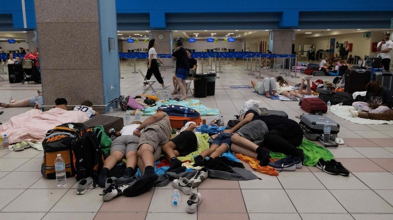 Wisatawan tidur sambil menunggu pesawat berangkat di bandara, setelah dievakuasi menyusul kebakaran hutan di pulau Rhodes, Yunani, (24/7/2023). (REUTERS/NICOLAS ECONOMOU)