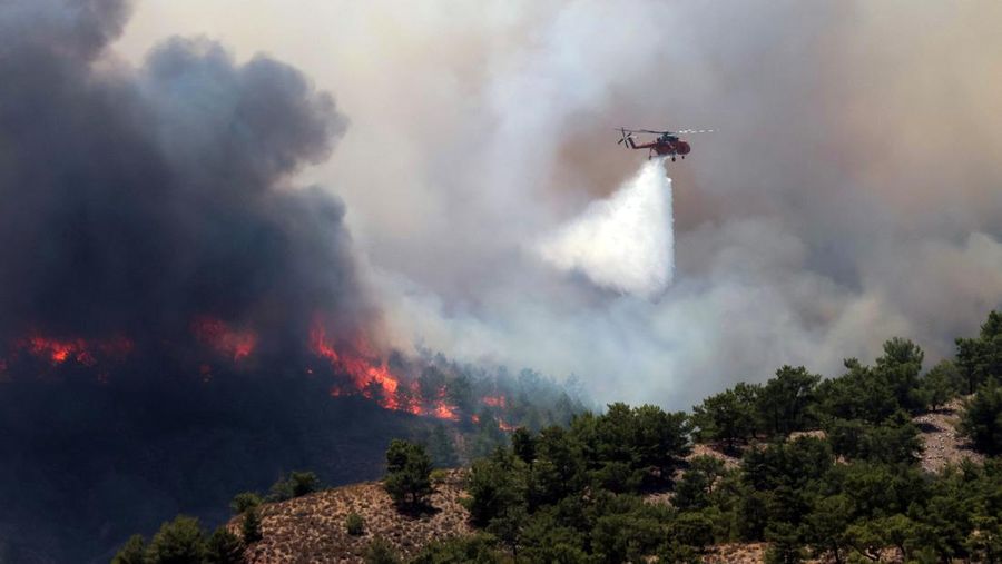 Helikopter pemadam kebakaran membuat tetesan air saat api membakar di dekat desa Archangelos, di pulau Rhodes, Yunani, 24 Juli 2023. (REUTERS/Nicolas Economou)