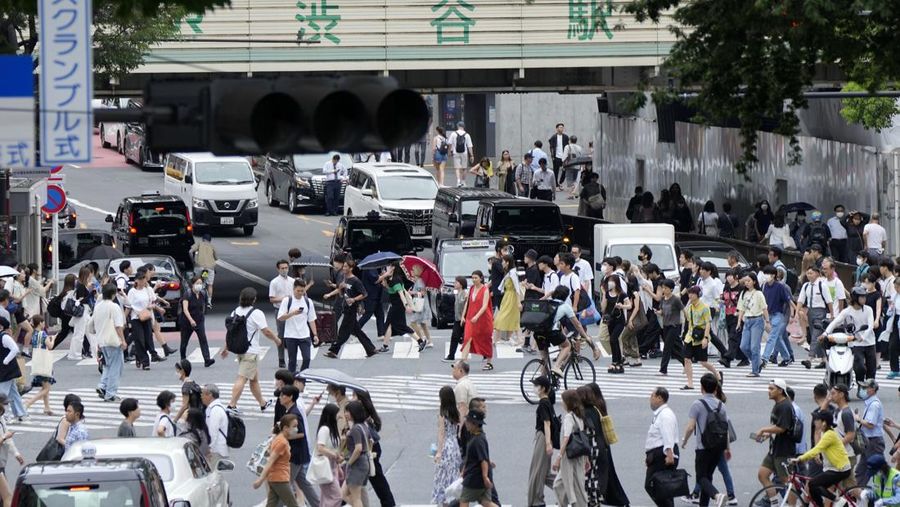 Orang-orang berjalan melintasi penyeberangan pejalan kaki di distrik Shibuya dalam cuaca panas dan lembab Kamis, 13 Juli 2023, di Tokyo. (AP Photo/Eugene Hoshiko)