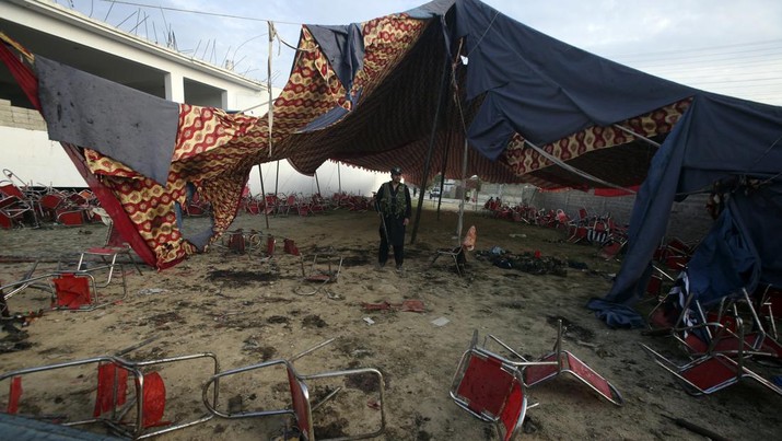 Seorang polisi Pakistan berjaga-jaga di lokasi serangan bom bunuh diri hari Minggu di distrik Bajur, Khyber Pakhtunkhwa, Pakistan, Senin, 31 Juli 2023. Seorang pembom bunuh diri meledakkan dirinya di rapat umum politik di bekas kubu militan di barat laut Pakistan berbatasan dengan Afghanistan pada hari Minggu, membunuh dan melukai banyak orang dalam serangan yang menurut seorang pemimpin senior dimaksudkan untuk melemahkan Islamis Pakistan. (AP Photo/Mohammad Sajjad)