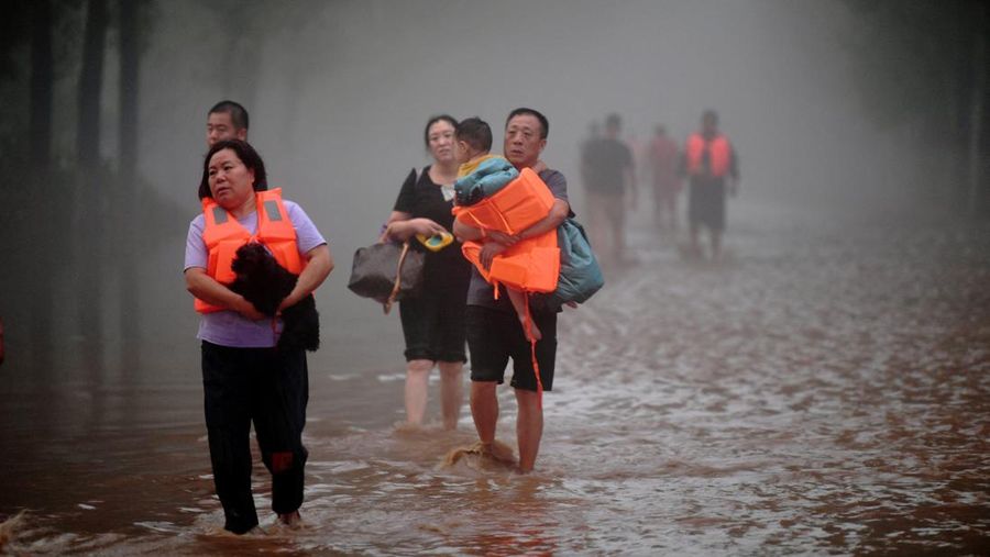 Warga mengarungi banjir setelah hujan deras di Zhuozhou, provinsi Hebei, China 1 Agustus 2023. (cnsphoto via REUTERS)