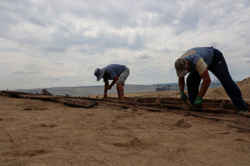 Arkeolog menggali lambung kapal kayu, sebuah kapal Romawi kuno dengan lambung datar di kota kuno Viminacium, dekat Kostolac, Serbia, 2 Agustus 2023. (REUTERS/Zorana Jevtic)