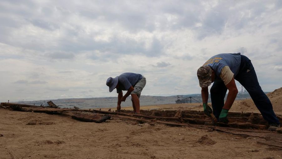 Arkeolog menggali lambung kapal kayu, sebuah kapal Romawi kuno dengan lambung datar di kota kuno Viminacium, dekat Kostolac, Serbia, 2 Agustus 2023. (REUTERS/Zorana Jevtic)