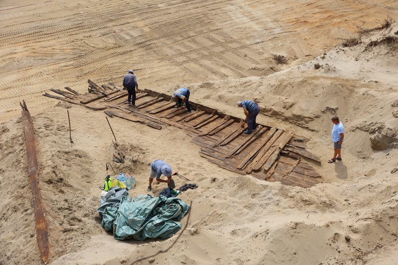 Arkeolog menggali lambung kapal kayu, sebuah kapal Romawi kuno dengan lambung datar di kota kuno Viminacium, dekat Kostolac, Serbia, 2 Agustus 2023. (REUTERS/Zorana Jevtic)