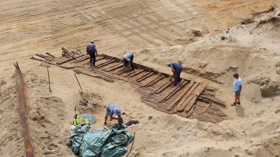 Arkeolog menggali lambung kapal kayu, sebuah kapal Romawi kuno dengan lambung datar di kota kuno Viminacium, dekat Kostolac, Serbia, 2 Agustus 2023. (REUTERS/Zorana Jevtic)