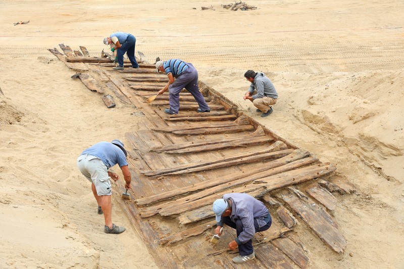 Arkeolog menggali lambung kapal kayu, sebuah kapal Romawi kuno dengan lambung datar di kota kuno Viminacium, dekat Kostolac, Serbia, 2 Agustus 2023. (REUTERS/Zorana Jevtic)
