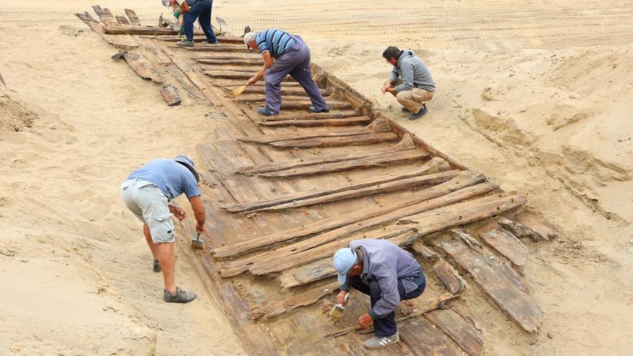Arkeolog menggali lambung kapal kayu, sebuah kapal Romawi kuno dengan lambung datar di kota kuno Viminacium, dekat Kostolac, Serbia, 2 Agustus 2023. (REUTERS/Zorana Jevtic)