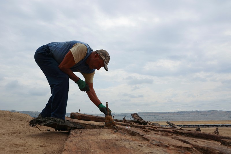 Arkeolog menggali lambung kapal kayu, sebuah kapal Romawi kuno dengan lambung datar di kota kuno Viminacium, dekat Kostolac, Serbia, 2 Agustus 2023. (REUTERS/Zorana Jevtic)