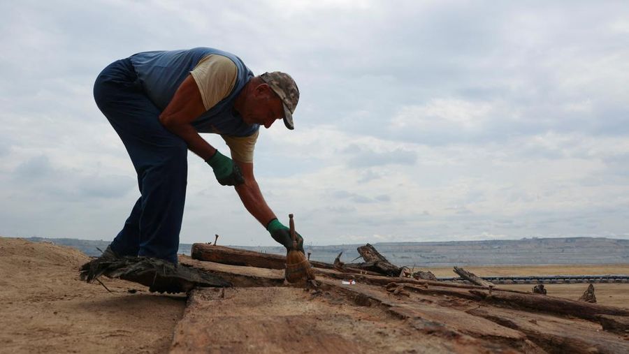 Arkeolog menggali lambung kapal kayu, sebuah kapal Romawi kuno dengan lambung datar di kota kuno Viminacium, dekat Kostolac, Serbia, 2 Agustus 2023. (REUTERS/Zorana Jevtic)