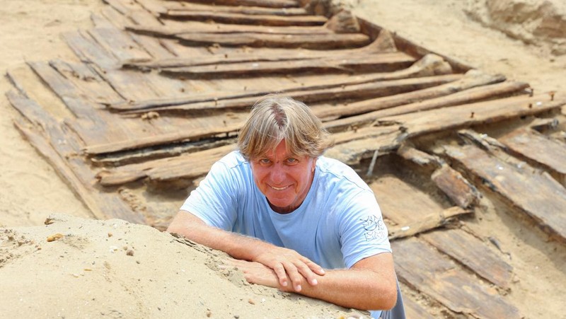 Arkeolog menggali lambung kapal kayu, sebuah kapal Romawi kuno dengan lambung datar di kota kuno Viminacium, dekat Kostolac, Serbia, 2 Agustus 2023. (REUTERS/Zorana Jevtic)