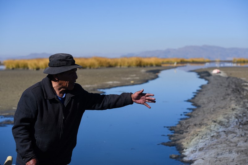 Isabel Apaza dan Gabriel Flores menaiki perahu mereka melalui jalur air sempit di dekat pantai Danau Titicaca pada musim kemarau di Huarina, Bolivia 3 Agustus 2023. (REUTERS/Claudia Morales)