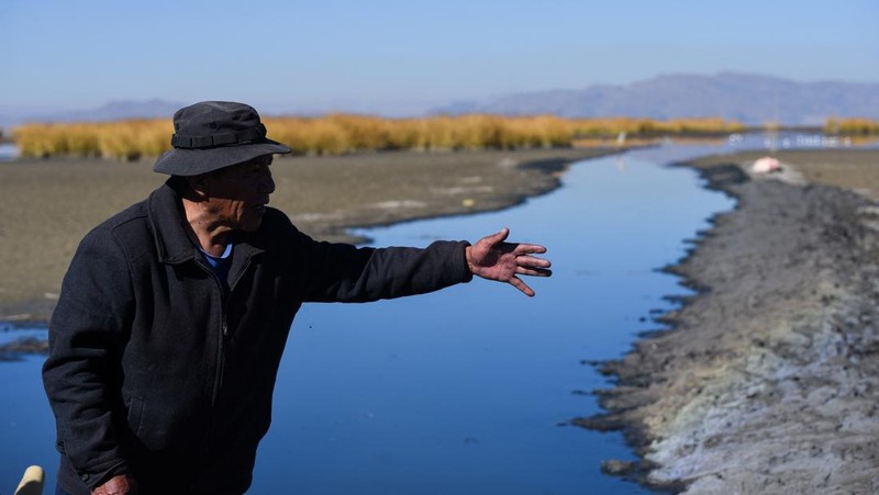 Isabel Apaza dan Gabriel Flores menaiki perahu mereka melalui jalur air sempit di dekat pantai Danau Titicaca pada musim kemarau di Huarina, Bolivia 3 Agustus 2023. (REUTERS/Claudia Morales)