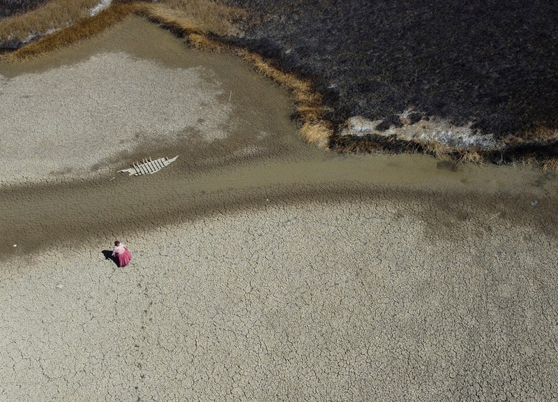 Isabel Apaza dan Gabriel Flores menaiki perahu mereka melalui jalur air sempit di dekat pantai Danau Titicaca pada musim kemarau di Huarina, Bolivia 3 Agustus 2023. (REUTERS/Claudia Morales)