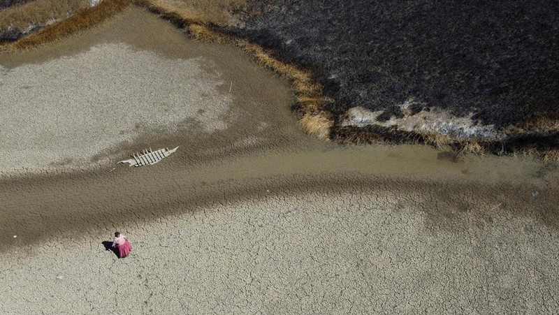 Isabel Apaza dan Gabriel Flores menaiki perahu mereka melalui jalur air sempit di dekat pantai Danau Titicaca pada musim kemarau di Huarina, Bolivia 3 Agustus 2023. (REUTERS/Claudia Morales)