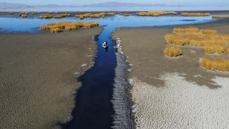 Isabel Apaza dan Gabriel Flores menaiki perahu mereka melalui jalur air sempit di dekat pantai Danau Titicaca pada musim kemarau di Huarina, Bolivia 3 Agustus 2023. (REUTERS/Claudia Morales)