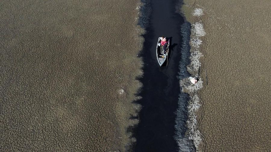 Isabel Apaza dan Gabriel Flores menaiki perahu mereka melalui jalur air sempit di dekat pantai Danau Titicaca pada musim kemarau di Huarina, Bolivia 3 Agustus 2023. (REUTERS/Claudia Morales)