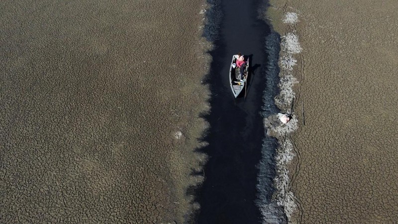Isabel Apaza dan Gabriel Flores menaiki perahu mereka melalui jalur air sempit di dekat pantai Danau Titicaca pada musim kemarau di Huarina, Bolivia 3 Agustus 2023. (REUTERS/Claudia Morales)