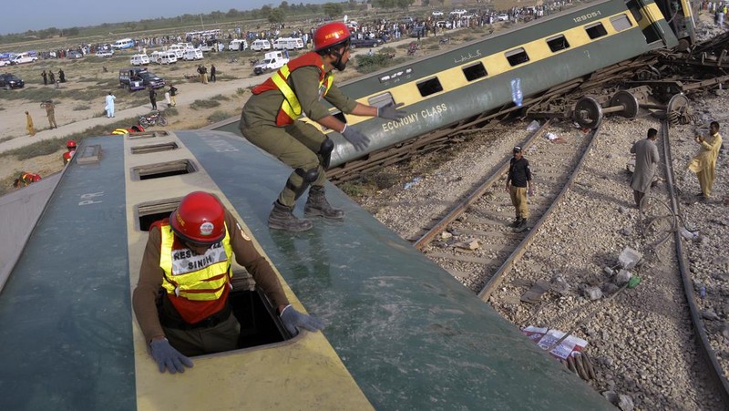 Petugas polisi berkumpul di lokasi kereta tergelincir di kota Sarhari di distrik Sanghar, Pakistan 6 Agustus 2023. (REUTERS/Yasir Rajput)