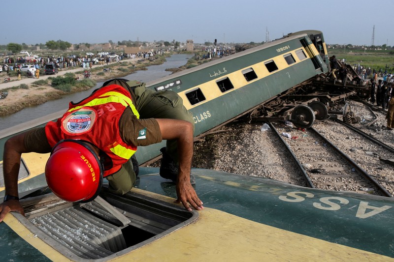 Petugas polisi berkumpul di lokasi kereta tergelincir di kota Sarhari di distrik Sanghar, Pakistan 6 Agustus 2023. (REUTERS/Yasir Rajput)