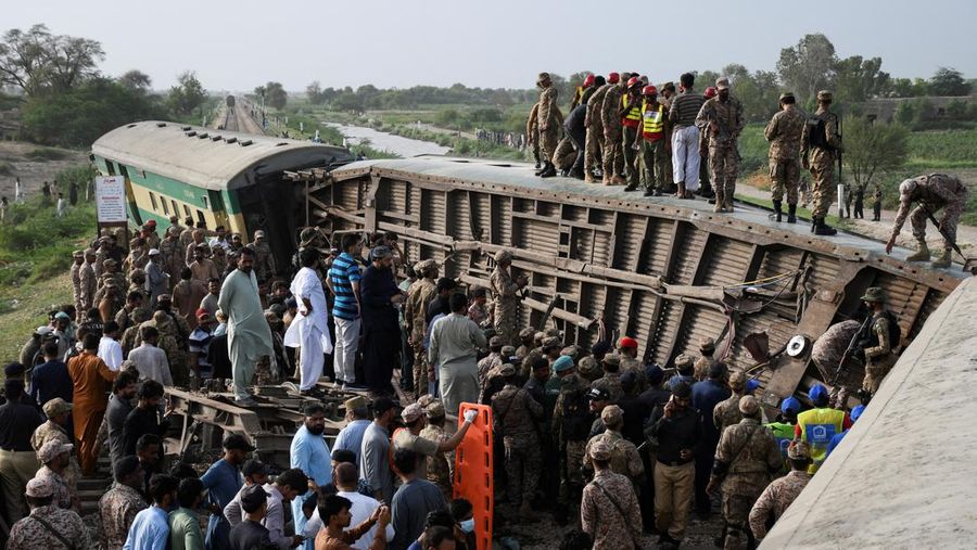 Petugas polisi berkumpul di lokasi kereta tergelincir di kota Sarhari di distrik Sanghar, Pakistan 6 Agustus 2023. (REUTERS/Yasir Rajput)