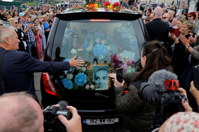 A hearse carrying the coffin of late Irish singer Sinead O'Connor passes outside her former home during her funeral procession as fans line the street to say their last goodbye to her, in Bray, Ireland, August 8, 2023. REUTERS/Clodagh Kilcoyne
