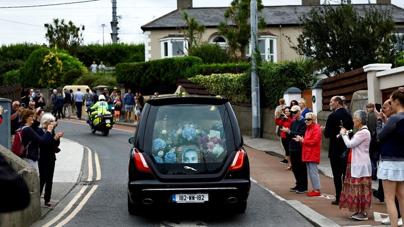 A hearse carrying the coffin of late Irish singer Sinead O'Connor passes outside her former home during her funeral procession as fans line the street to say their last goodbye to her, in Bray, Ireland, August 8, 2023. REUTERS/Clodagh Kilcoyne
