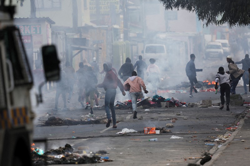 SAFRICA-TAXI/STRIKE A resident of Masiphumelele use a board as a shield during clashes with law enforcement officers amidst an ongoing strike by taxi operators against traffic authorities in Cape Town, South Africa, August 8, 2023. REUTERS/Esa Alexander