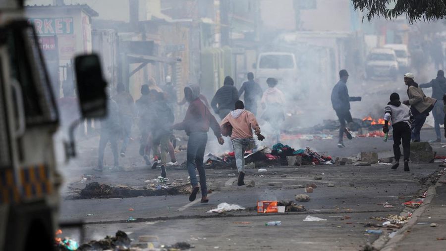 A resident of Masiphumelele use a board as a shield during clashes with law enforcement officers amidst an ongoing strike by taxi operators against traffic authorities in Cape Town, South Africa, August 8, 2023. REUTERS/Esa Alexander