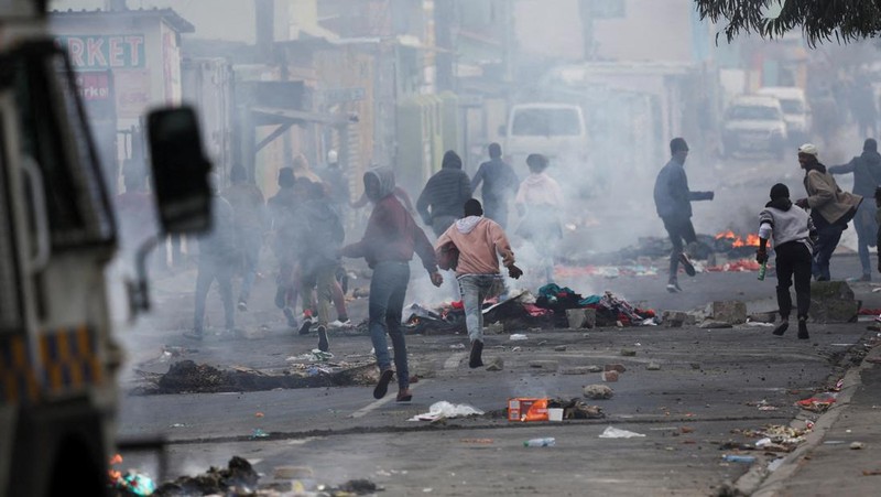 A resident of Masiphumelele use a board as a shield during clashes with law enforcement officers amidst an ongoing strike by taxi operators against traffic authorities in Cape Town, South Africa, August 8, 2023. REUTERS/Esa Alexander
