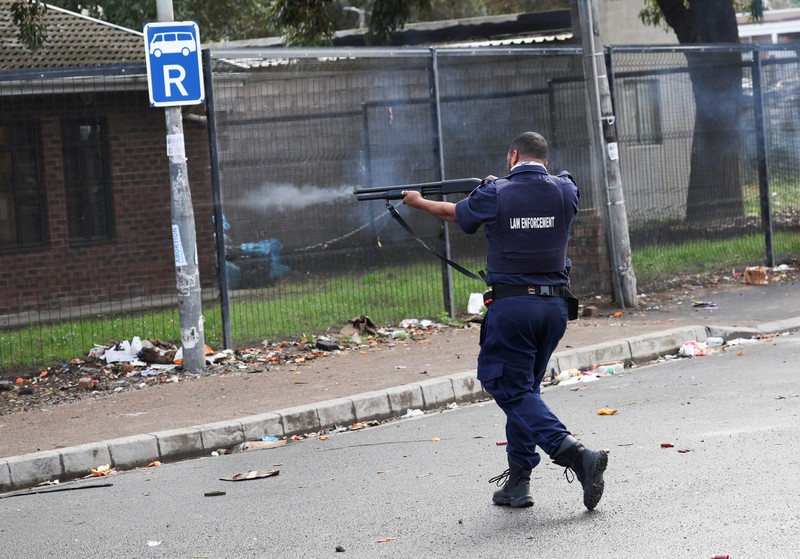 SAFRICA-TAXI/STRIKE A resident of Masiphumelele use a board as a shield during clashes with law enforcement officers amidst an ongoing strike by taxi operators against traffic authorities in Cape Town, South Africa, August 8, 2023. REUTERS/Esa Alexander