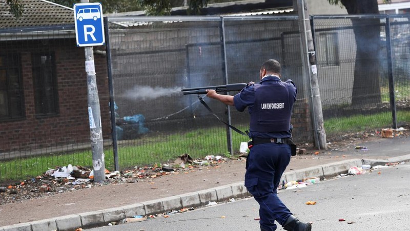A resident of Masiphumelele use a board as a shield during clashes with law enforcement officers amidst an ongoing strike by taxi operators against traffic authorities in Cape Town, South Africa, August 8, 2023. REUTERS/Esa Alexander