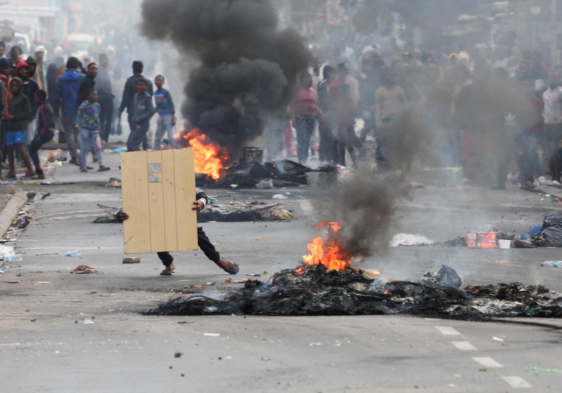 SAFRICA-TAXI/STRIKE A resident of Masiphumelele use a board as a shield during clashes with law enforcement officers amidst an ongoing strike by taxi operators against traffic authorities in Cape Town, South Africa, August 8, 2023. REUTERS/Esa Alexander