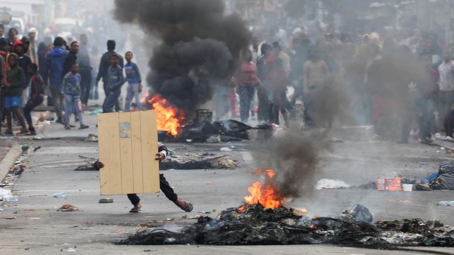 A resident of Masiphumelele use a board as a shield during clashes with law enforcement officers amidst an ongoing strike by taxi operators against traffic authorities in Cape Town, South Africa, August 8, 2023. REUTERS/Esa Alexander