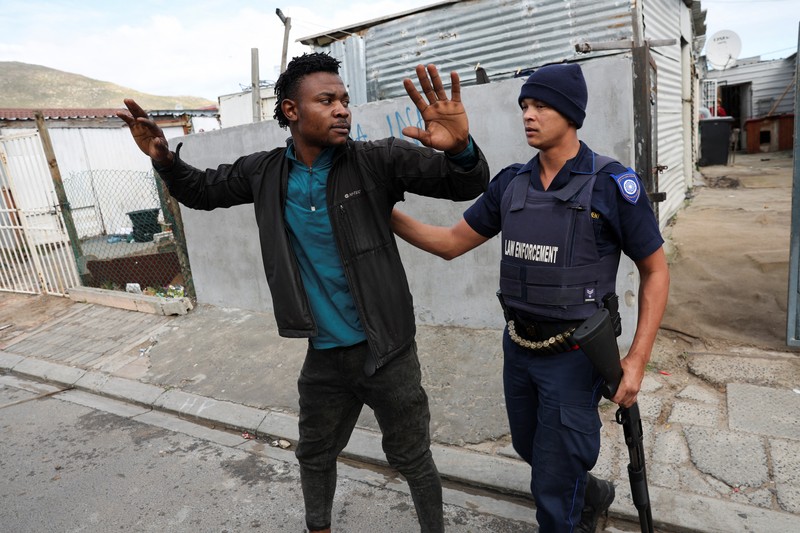SAFRICA-TAXI/STRIKE A resident of Masiphumelele use a board as a shield during clashes with law enforcement officers amidst an ongoing strike by taxi operators against traffic authorities in Cape Town, South Africa, August 8, 2023. REUTERS/Esa Alexander