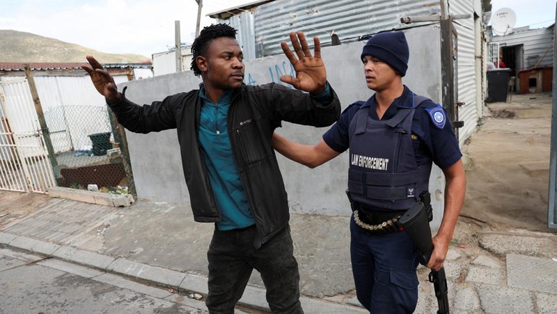 A resident of Masiphumelele use a board as a shield during clashes with law enforcement officers amidst an ongoing strike by taxi operators against traffic authorities in Cape Town, South Africa, August 8, 2023. REUTERS/Esa Alexander