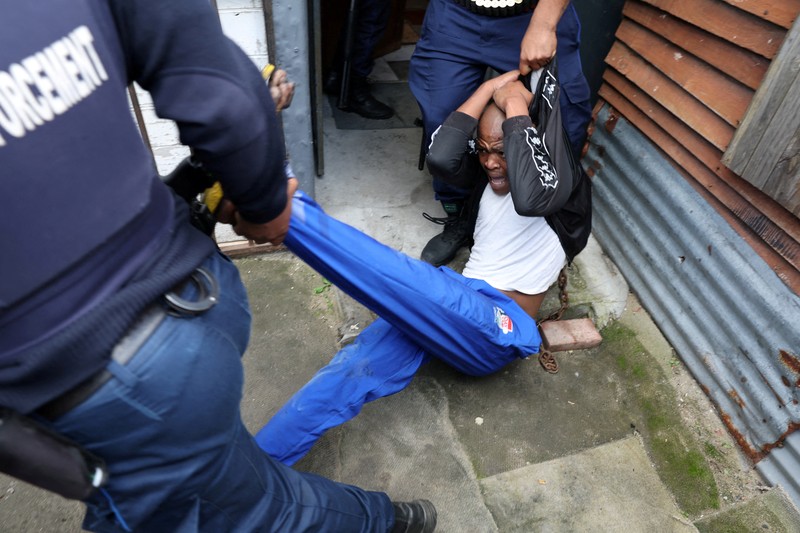 SAFRICA-TAXI/STRIKE A resident of Masiphumelele use a board as a shield during clashes with law enforcement officers amidst an ongoing strike by taxi operators against traffic authorities in Cape Town, South Africa, August 8, 2023. REUTERS/Esa Alexander