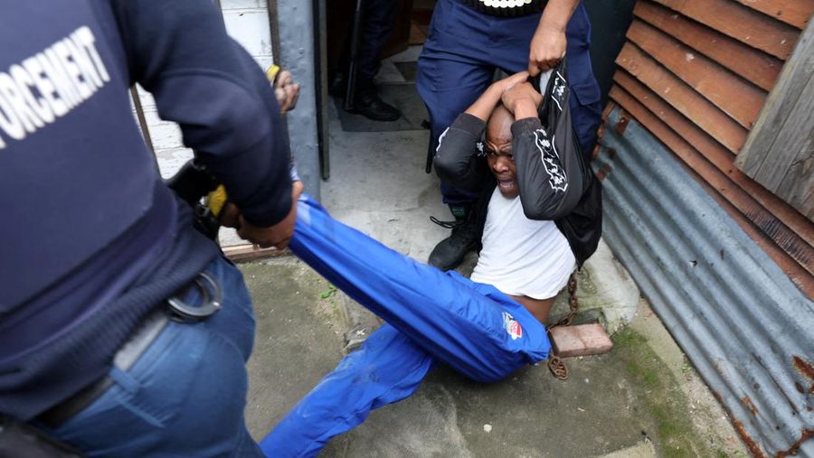 A resident of Masiphumelele use a board as a shield during clashes with law enforcement officers amidst an ongoing strike by taxi operators against traffic authorities in Cape Town, South Africa, August 8, 2023. REUTERS/Esa Alexander