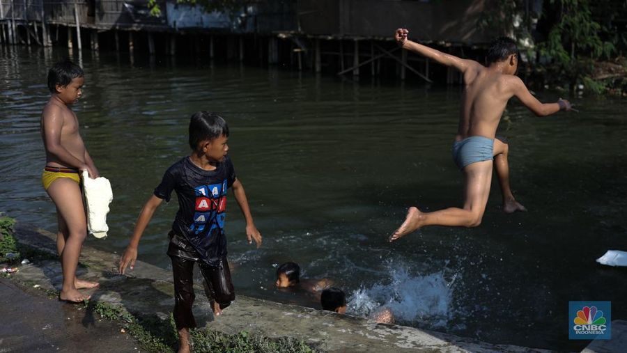 Sejumlah anak-anak bermain air di saluran anak kali Cisadane, Desa Belimbing, Kecamatan Pasar Kemis, Kabupaten Tangerang, Banten, Rabu (9/8/2023). (CNBC Indonesia/Tri Susilo)