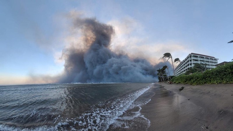 Orang-orang menyaksikan asap dan api memenuhi udara dari amukan kebakaran hutan di Front Street di pusat kota Lahaina, Maui pada Selasa, 8 Agustus 2023. Para pejabat Maui mengatakan kebakaran di kota bersejarah itu telah menghanguskan sebagian dari salah satu kawasan wisata paling populer di Hawaii. . Juru bicara County of Maui, Mahina Martin mengatakan dalam sebuah wawancara telepon pada Rabu pagi, kebakaran meluas di Lahaina, termasuk Front Street, area kota yang populer dengan turis. (Alan Dickar via AP)