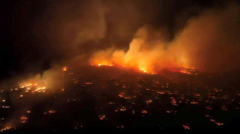 Orang-orang menyaksikan asap dan api memenuhi udara dari amukan kebakaran hutan di Front Street di pusat kota Lahaina, Maui pada Selasa, 8 Agustus 2023. Para pejabat Maui mengatakan kebakaran di kota bersejarah itu telah menghanguskan sebagian dari salah satu kawasan wisata paling populer di Hawaii. . Juru bicara County of Maui, Mahina Martin mengatakan dalam sebuah wawancara telepon pada Rabu pagi, kebakaran meluas di Lahaina, termasuk Front Street, area kota yang populer dengan turis. (Alan Dickar via AP)