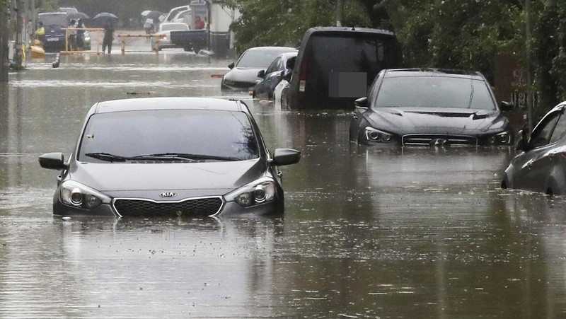 People struggle in the rain and wind as the tropical storm named Khanun approaches to the Korean Peninsular, in Busan, Thursday, Aug. 10, 2023. (AP Photo/Ahn Young-joon)