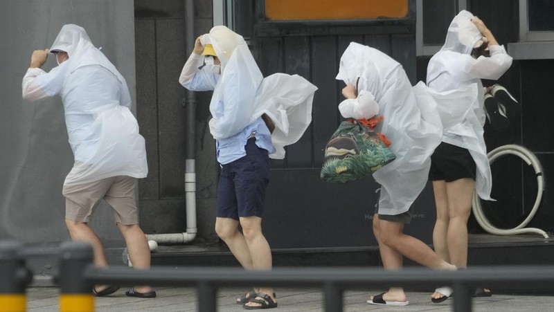 People struggle in the rain and wind as the tropical storm named Khanun approaches to the Korean Peninsular, in Busan, Thursday, Aug. 10, 2023. (AP Photo/Ahn Young-joon)